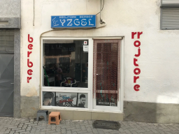 Hyrja e rrojtores me tabelë blu dhe shkronja të kuqe vertikale