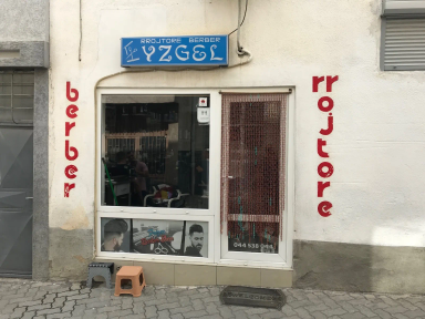 Hyrja e rrojtores me tabelë blu dhe shkronja të kuqe vertikale